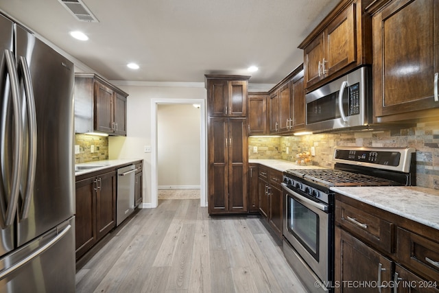 kitchen with light wood-type flooring, ornamental molding, appliances with stainless steel finishes, tasteful backsplash, and dark brown cabinets