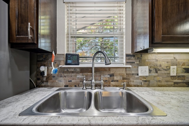 kitchen featuring dark brown cabinetry, light stone counters, and sink