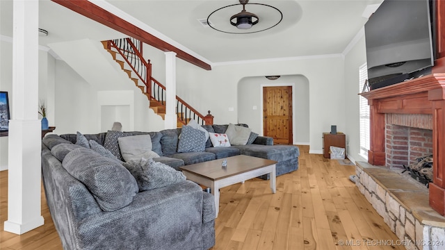 living room featuring ornamental molding, light wood-type flooring, a fireplace, and ceiling fan