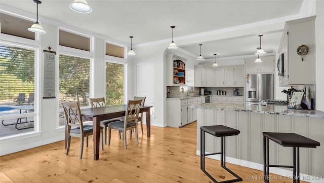 kitchen with light stone countertops, light hardwood / wood-style floors, appliances with stainless steel finishes, and a wealth of natural light