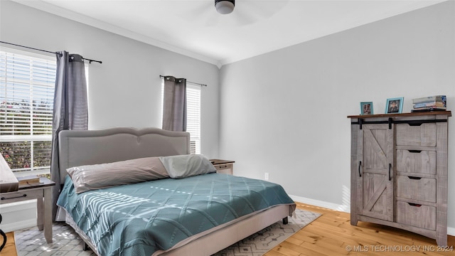 bedroom featuring multiple windows, ceiling fan, a barn door, and light hardwood / wood-style flooring