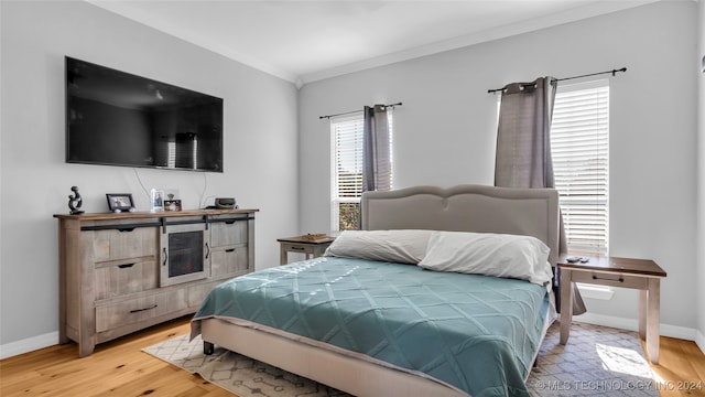 bedroom featuring light hardwood / wood-style flooring, crown molding, and multiple windows