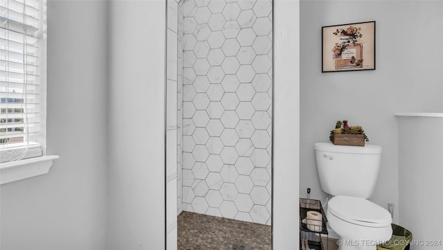 bathroom featuring a tile shower and toilet