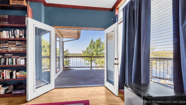 doorway with french doors, wood-type flooring, ornamental molding, and plenty of natural light