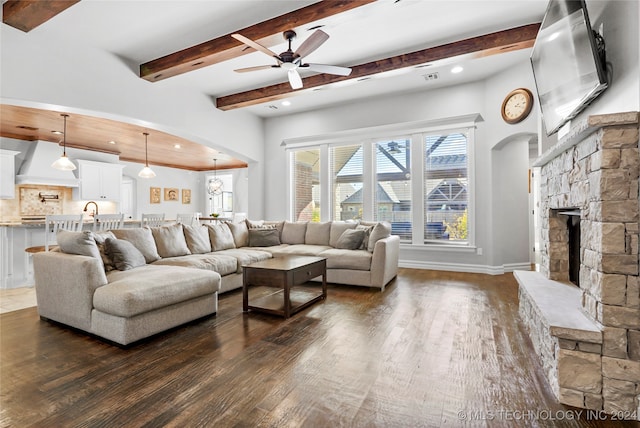 living room with ceiling fan, a fireplace, beamed ceiling, and dark hardwood / wood-style floors