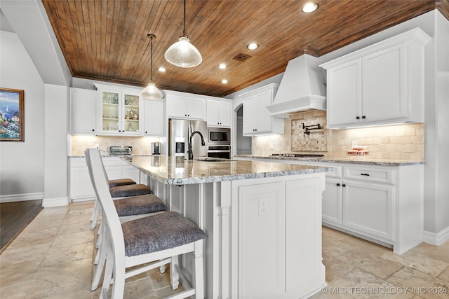 kitchen featuring a kitchen island with sink, wood ceiling, white cabinetry, premium range hood, and appliances with stainless steel finishes