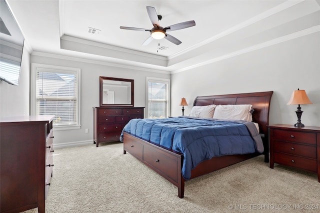 carpeted bedroom with ceiling fan, a raised ceiling, and ornamental molding