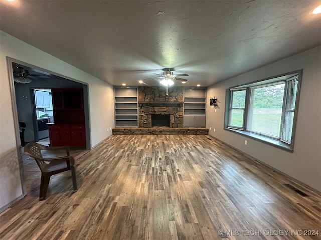 unfurnished living room featuring a fireplace, wood-type flooring, built in features, and ceiling fan