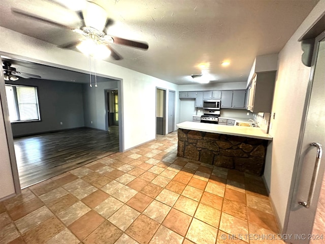 kitchen featuring gray cabinetry, ceiling fan, light hardwood / wood-style flooring, kitchen peninsula, and appliances with stainless steel finishes