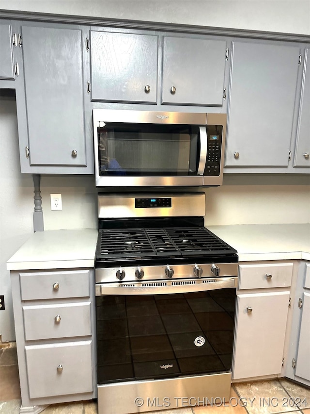 kitchen with appliances with stainless steel finishes, light tile patterned floors, and gray cabinetry