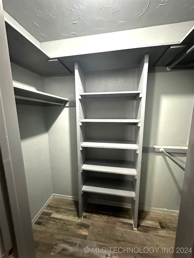 walk in closet with dark wood-type flooring