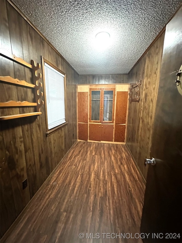 unfurnished room featuring wood walls, hardwood / wood-style flooring, and a textured ceiling