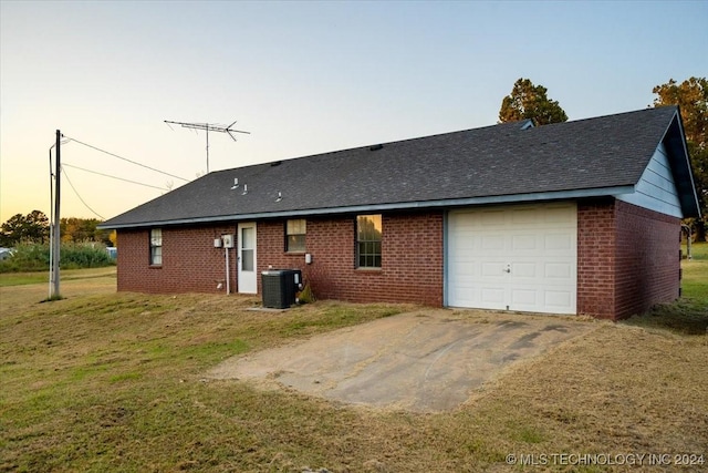 exterior space featuring a yard, central AC unit, and a garage