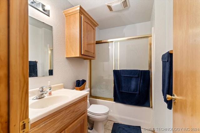 full bathroom featuring a textured ceiling, vanity, shower / bath combination with glass door, tile patterned flooring, and toilet