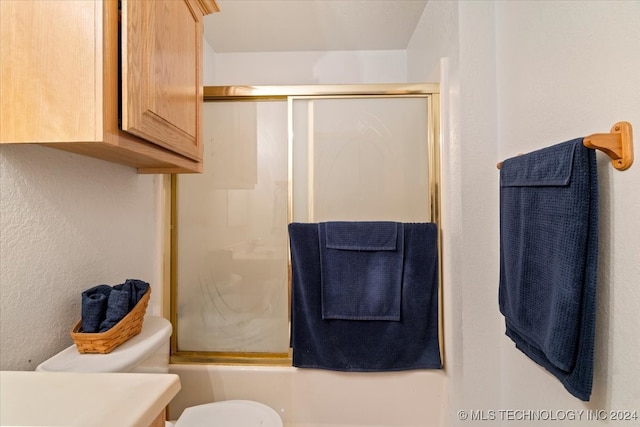 bathroom with toilet and combined bath / shower with glass door