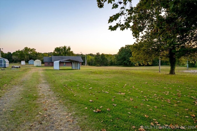 yard at dusk with an outbuilding and a carport