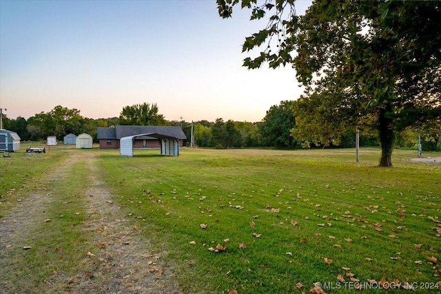 711 E Iowa, Whitefield, OK 74472 - yard at dusk featuring a storage shed, driveway, an outbuilding, and a detached carport