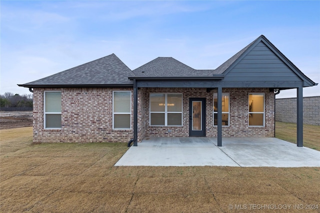 back of property featuring a yard, a shingled roof, and brick siding