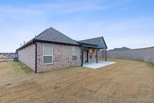 rear view of house with a patio area, a yard, and central AC