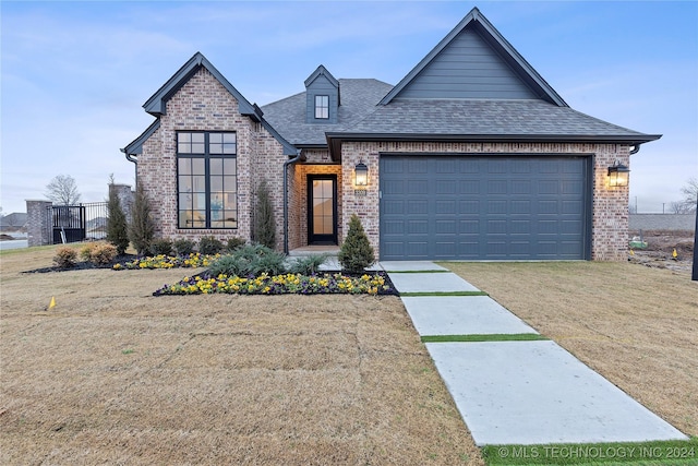 view of front of property with a garage, brick siding, a shingled roof, driveway, and a front lawn