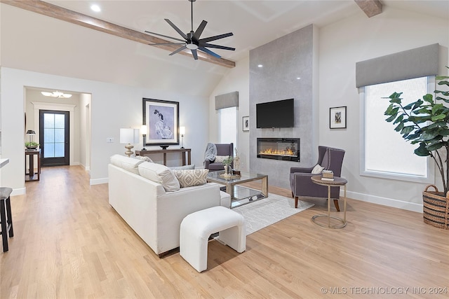 living room with vaulted ceiling with beams, a large fireplace, ceiling fan, and light hardwood / wood-style flooring