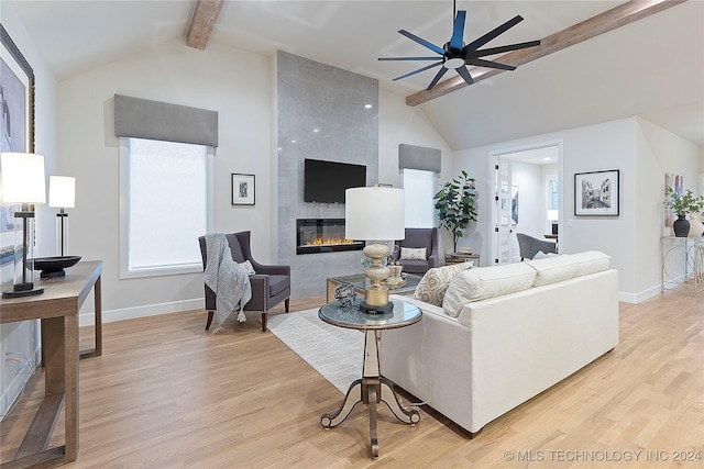 living room featuring ceiling fan, a large fireplace, lofted ceiling with beams, and light hardwood / wood-style floors