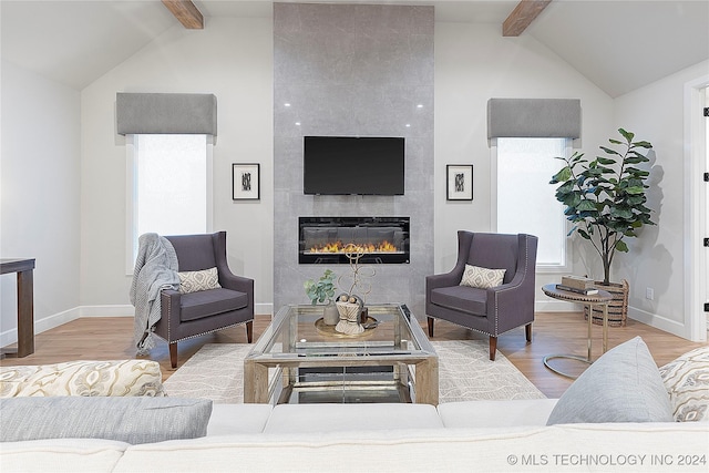 living room with lofted ceiling with beams, light wood-type flooring, and a fireplace