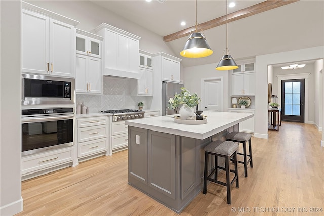 kitchen with a center island, white cabinetry, stainless steel appliances, and tasteful backsplash