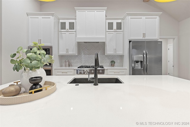 kitchen with decorative backsplash, white cabinetry, stainless steel refrigerator with ice dispenser, and vaulted ceiling