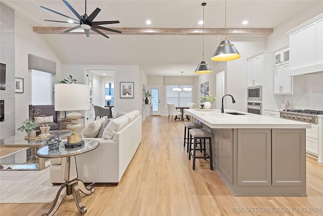 kitchen with appliances with stainless steel finishes, light wood-style floors, open floor plan, and a sink