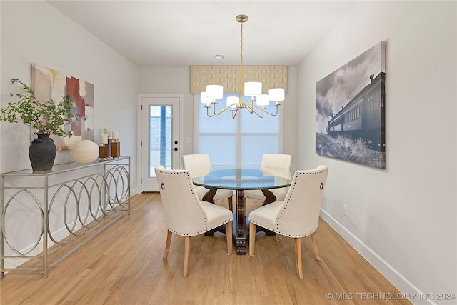 dining space featuring a notable chandelier, visible vents, baseboards, and wood finished floors