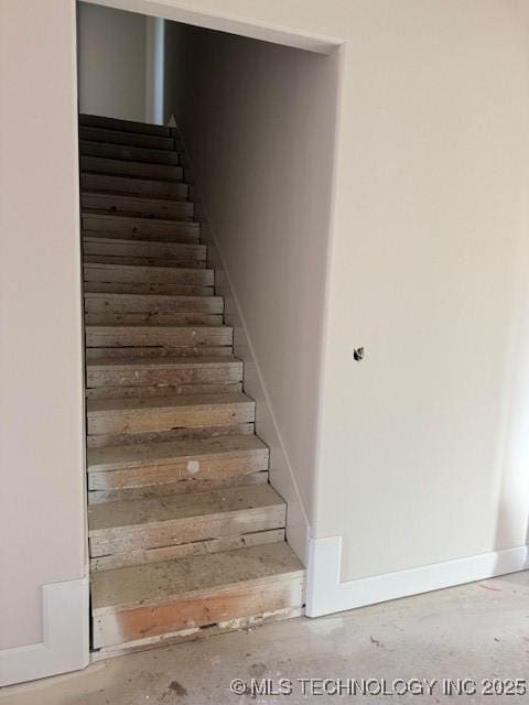 staircase featuring unfinished concrete floors