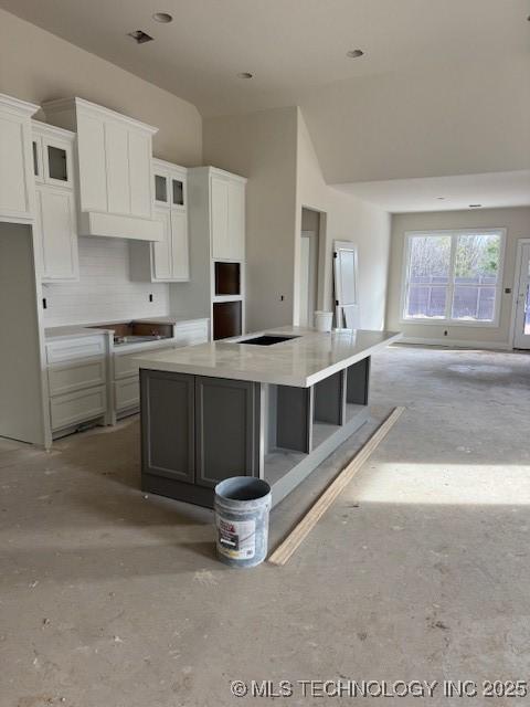 kitchen with a spacious island, light countertops, a towering ceiling, glass insert cabinets, and white cabinets