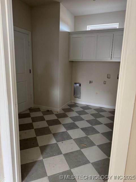 laundry room featuring baseboards, cabinet space, and light floors