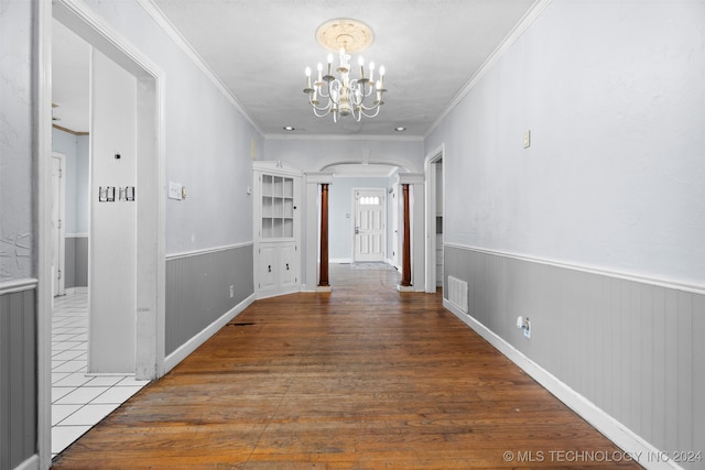 hallway featuring hardwood / wood-style flooring, crown molding, and an inviting chandelier