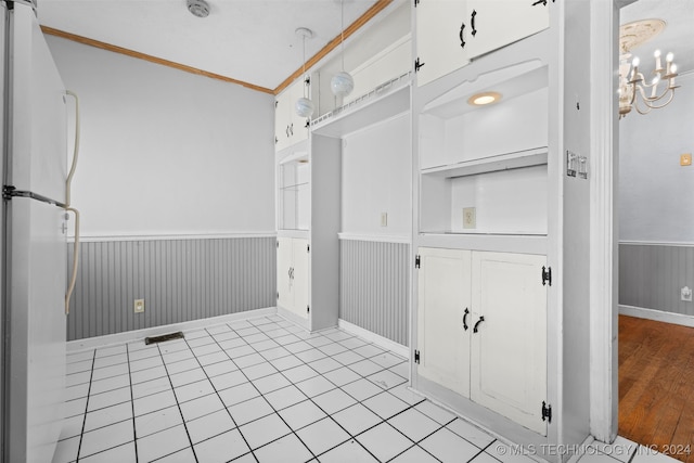 interior space featuring light hardwood / wood-style floors, white cabinetry, a chandelier, crown molding, and white fridge