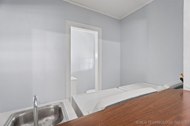 bathroom featuring washer / dryer, sink, and ornamental molding