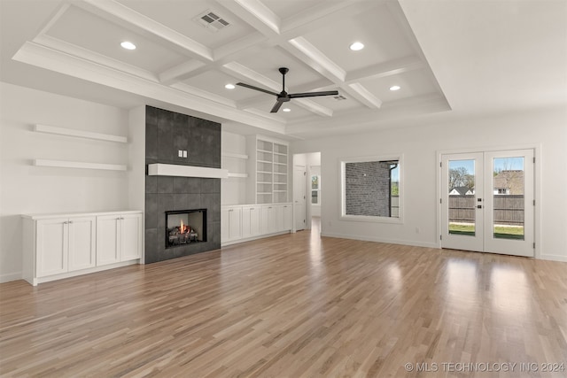 unfurnished living room featuring coffered ceiling, visible vents, french doors, light wood-type flooring, and a tiled fireplace