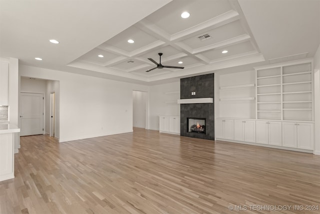 unfurnished living room with ceiling fan, beamed ceiling, coffered ceiling, a large fireplace, and light hardwood / wood-style floors