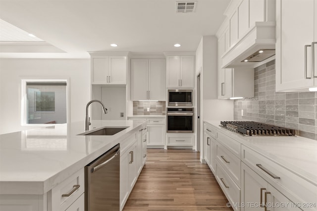 kitchen featuring stainless steel appliances, tasteful backsplash, sink, light hardwood / wood-style floors, and white cabinetry