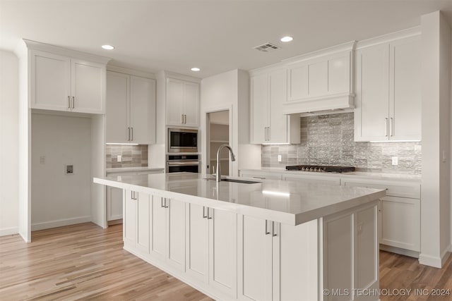 kitchen featuring stainless steel appliances, light countertops, a sink, and an island with sink