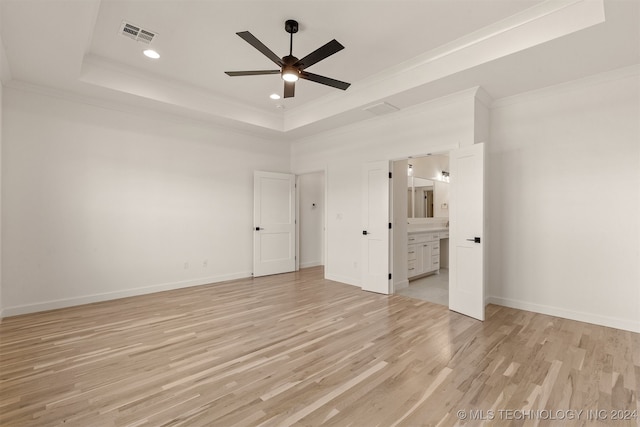 unfurnished bedroom featuring visible vents, baseboards, a tray ceiling, light wood finished floors, and crown molding