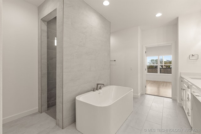 bathroom featuring tile patterned flooring, separate shower and tub, vanity, and tile walls