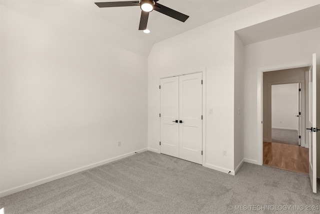 unfurnished bedroom with ceiling fan, light carpet, baseboards, vaulted ceiling, and a closet