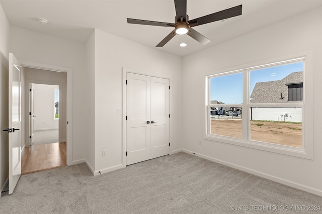 unfurnished bedroom featuring a closet, light carpet, and ceiling fan