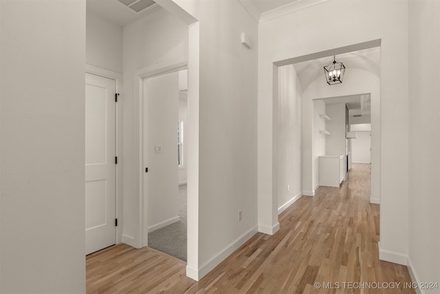 hallway with baseboards, light wood-type flooring, visible vents, and an inviting chandelier