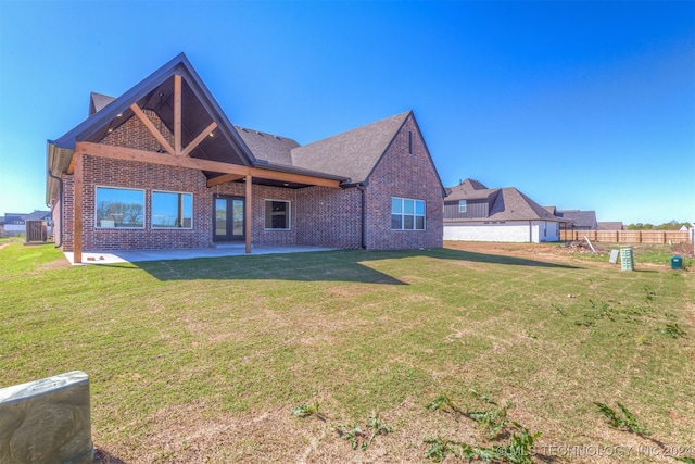 back of house featuring brick siding, fence, a patio, and a lawn