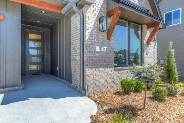 property entrance with brick siding and a patio area