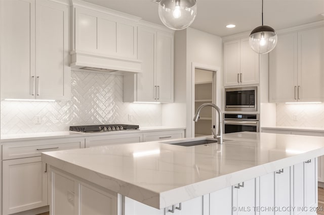 kitchen with white cabinets, an island with sink, stainless steel appliances, and sink