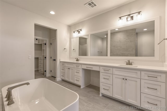 full bathroom featuring double vanity, a freestanding tub, visible vents, and a sink